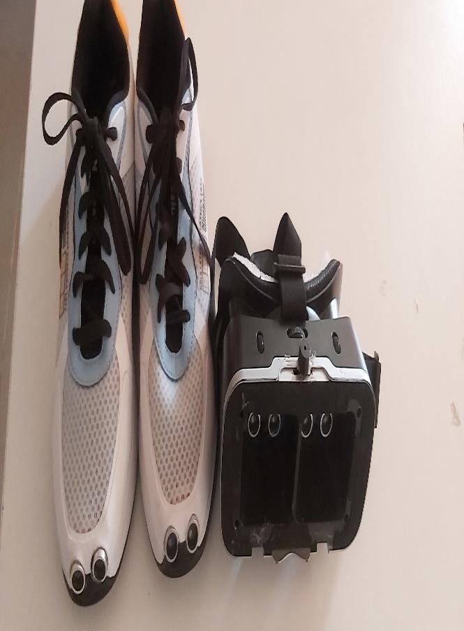 The Third Eye Kit laid out from above: a pair of trainers fitted with sensor housings at the toes, beside the glasses rig with its ultrasonic sensor and wired electronics. Photographed in 2022 and tinted amber.